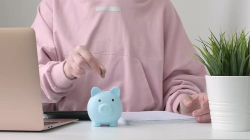Frau legt Münzen ins Sparschwein