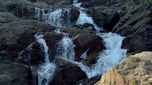 Le mouvement de l'eau au ralenti tombant sur les rochers depuis une cascade de montagne