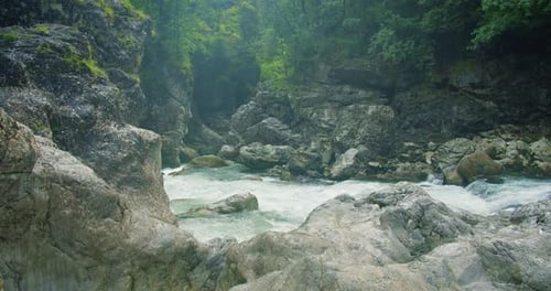 Evaporation over a cold mountain river with clear water in rocky gorge. Spring nature landscape.