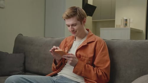 Young Adult Using Mobile Phone on Sofa Indoors