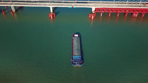 Barge Travels on River Under Concrete Bridge During the Day
