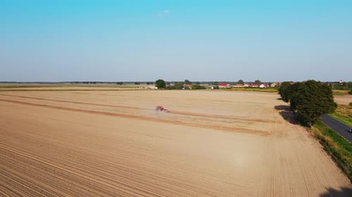 Tractor Working in Agricultural Field Cultivating and Plowing Dry Soil
