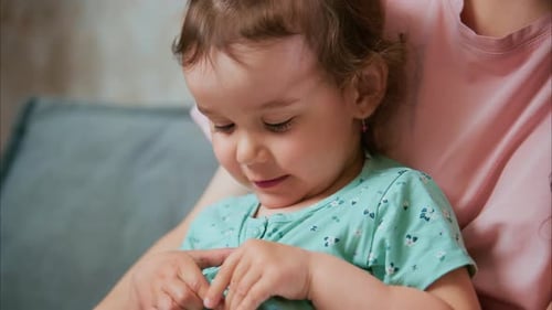 Toddler Sitting on Lap and Playing with Toy