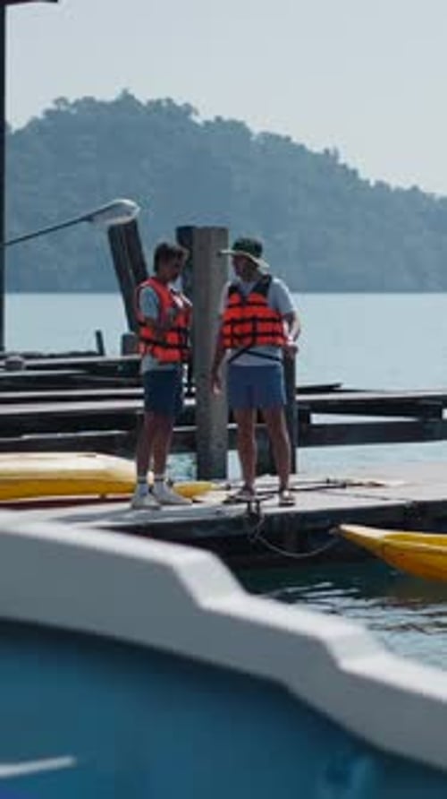 Tourists Preparing for a Kayaking Adventure on a Wooden Pier By the Lake