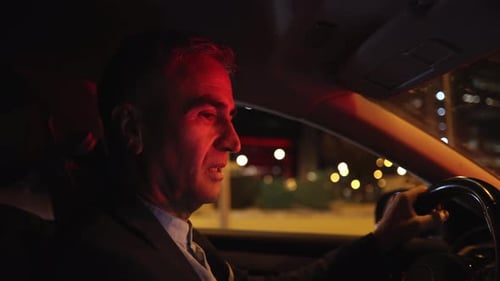 mature man driving through the city at night, serious