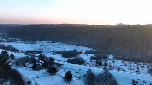 A serene winter scene featuring a snowcovered forest and a quiet rural area at sunrise. Smooth