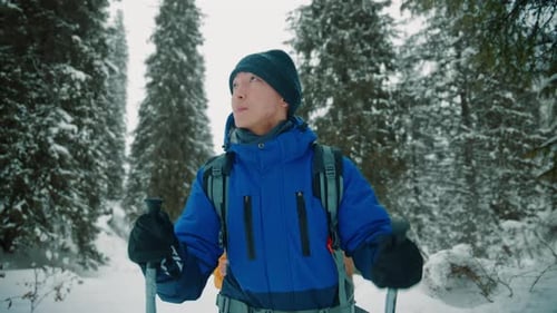 Asian man trekking in a snowy winter forest