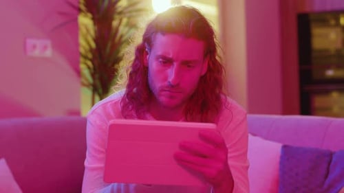 Man Uses Tablet Device on Couch at Home