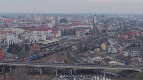 Aerial view of a dense urban city with railway lines, trains, and an elevated highway crossing