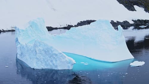 Massiver geformter Eisberg, der in ruhigen dunkelblauen Polargewässern schwimmt