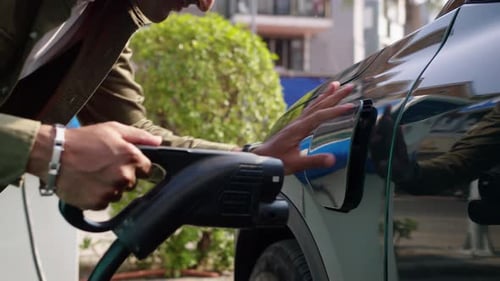 Man Plugging Cable in Charging Port of Electric Car Cropped Shot