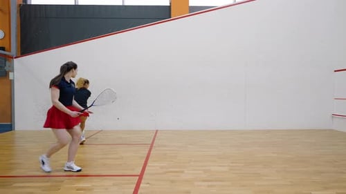 Female Players Alternate in Striking Squash Ball with Racket