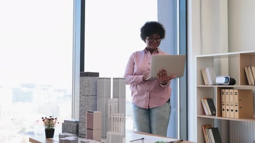 African American Architect Designing Modern Building on Laptop