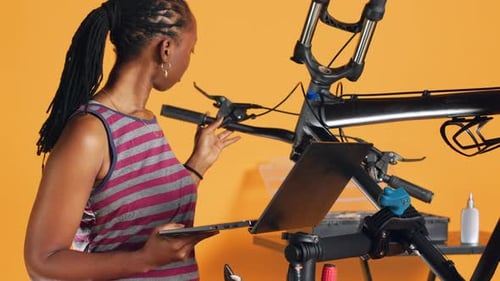 Engineer Does Bike Servicing Looking on Laptop Maintenance List Studio Background