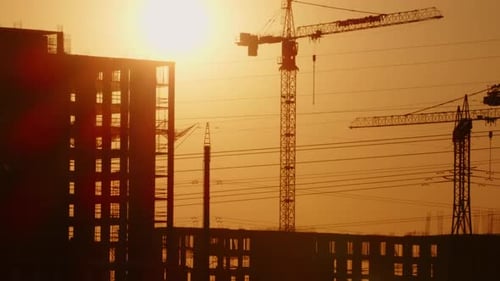 Timelapse sun sets on construction sites of buildings houses with tower cranes.
