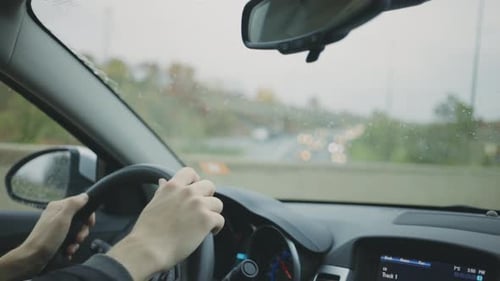 Hands On The Steering Wheel While Driving On The Road On A Rainy Day - Travel Concept - close up