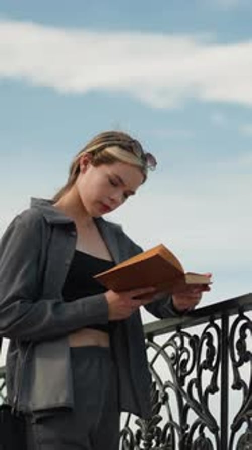 Young Woman Reading Book on City Street