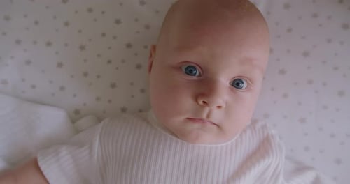 Close Up of Sweet Beautiful Newborn Baby Lying on Bed Sheets