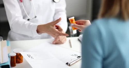 Doctor Hands Prescription Bottle to Patient in Office