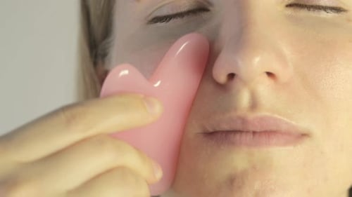 Woman Giving Herself a Facial Massage with Gua Sha