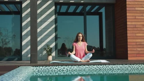 Femme détendue méditant près de la piscine dans une maison de luxe. Jeune femme faisant des exercices de yoga. Femme d'affaires...