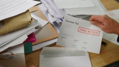 Close up of a man opening debt letters. The letter shows an income tax bill final notice