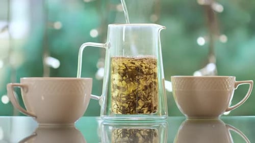 Pouring green hot tea into white cups outside. Healthy antioxidant drink