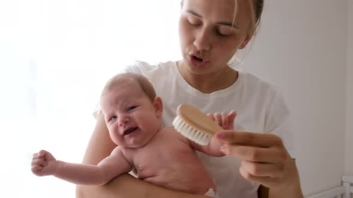 Parent Brushing Hair of Adorable Infant at Home