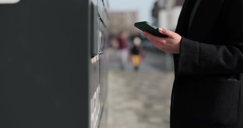 Close Up Woman Receiving Parcel From Post Terminal Machine Using Smartphone Mail Delivery and Post
