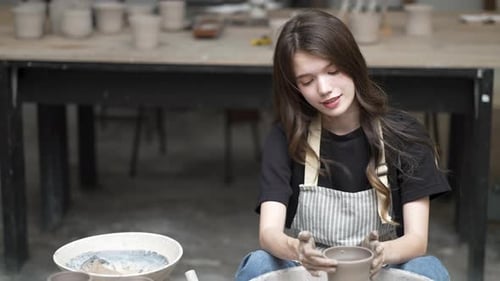 Young women is making earthenware at workshop.