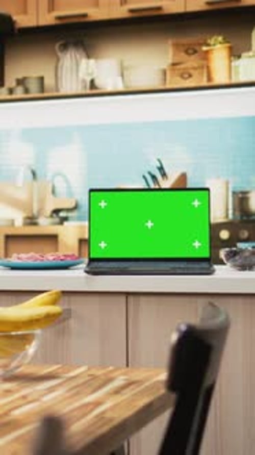 Vertical Video Green Screen on a Laptop Placed on Empty Table in Rustic Kitchen Space