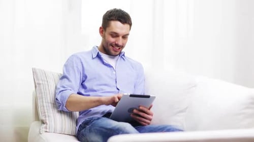 Man Relaxing on Couch Using Tablet