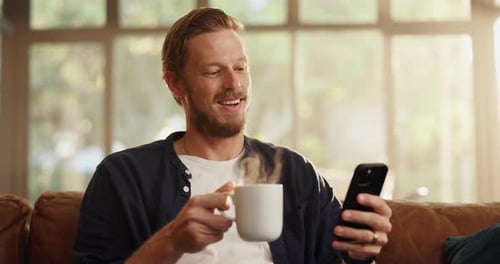 Man Smiling While Using a Phone and Drinking