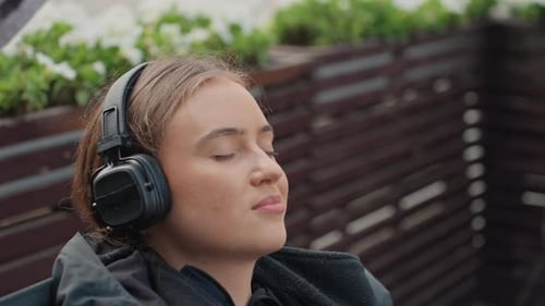 Serene Woman Listens to Music with Wireless Headphones Outdoors