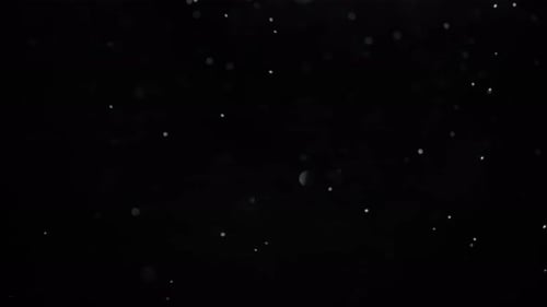 Close up of snow falling to the left in front of a black background