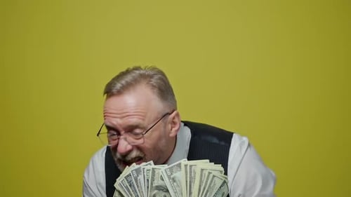 Happy old man with dollars in his hands. Positive rich man demonstrates his money.