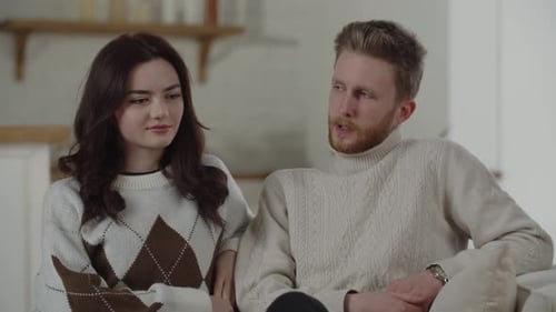 Young Adults Conversing Comfortably on a Couch Indoors