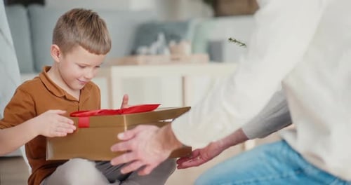 Boy Joyfully Opening a Christmas Gift at Home