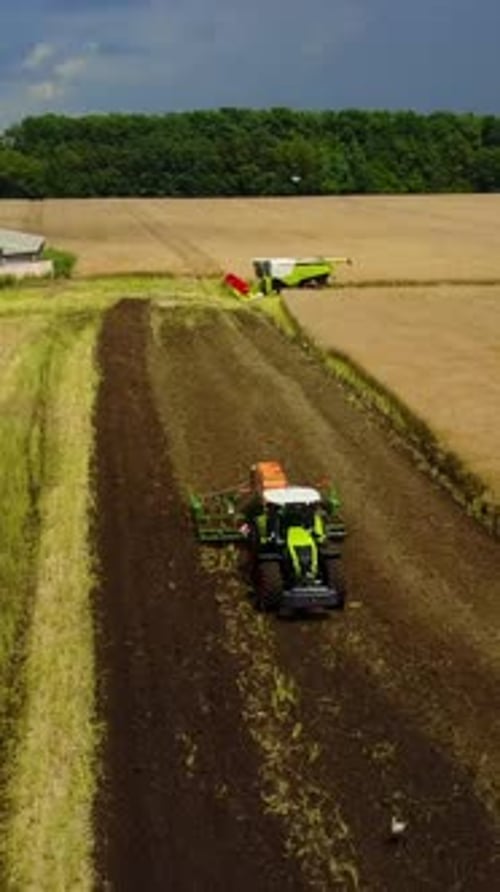 Green Tractor Working In A Field. Aerial shot of the green tractor working in a field or farmland