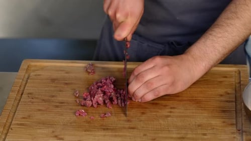 Adult Male Cuts Meat on Wood Cutting Board