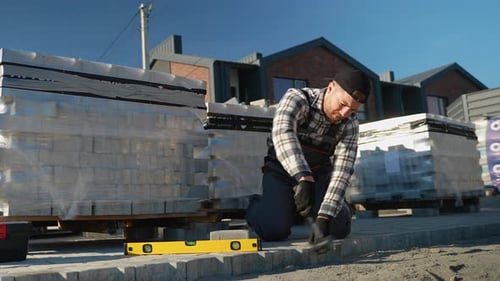 Construction Worker Laying Paving Stones on Street