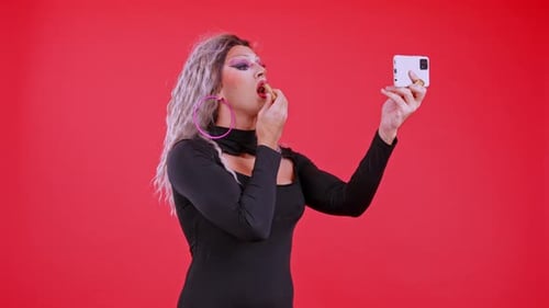 Person Applying Lipstick in front of Red Backdrop