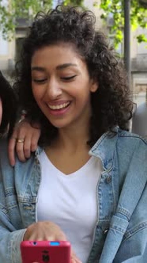 Two Young Adults Look at Phone and Smile