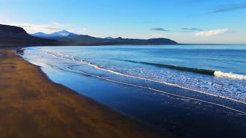 Aerial View of Black Sand Volcanic Beach with Crashing Waves Cinematic Long Drone Shot Serene and