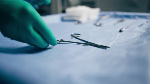 Closeup in Operating Room the Lower Surgeon in Green Gloves Lays Out Instruments on the Surgical