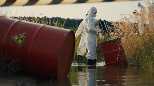 Workers in Protective Suits Inspecting Toxic Waste Barrels