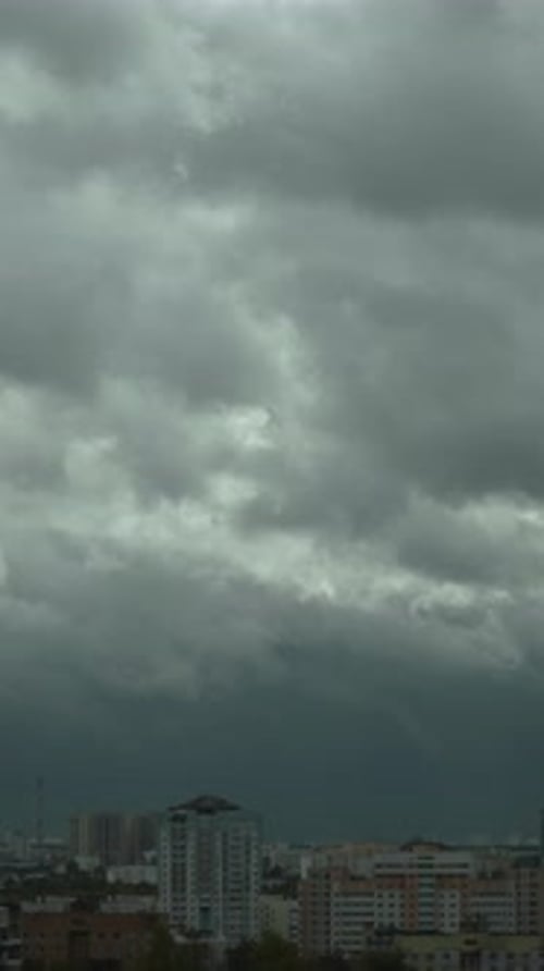 Vertical Video of Gray Low Heavy Clouds Moving Quickly Over City Buildings