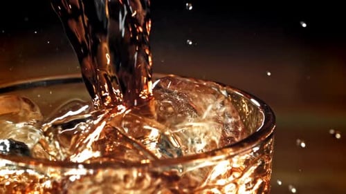Refreshing Dark Liquid Poured Into a Glass with Ice