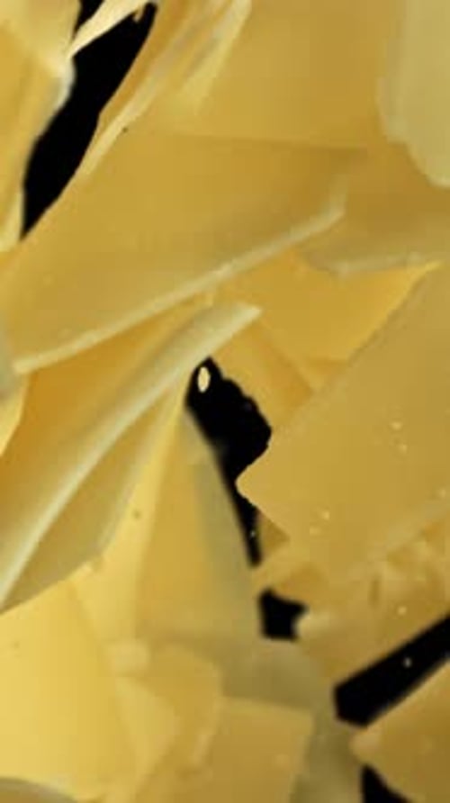 Parmesan Cheese Flakes Fly Upwards on a Black Background Filmed on a Highspeed Camera at 1000 Fps