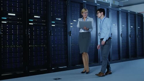 In the Modern Data Center: Engineer and IT Specialist Work with Server Racks, Talking, Doing System